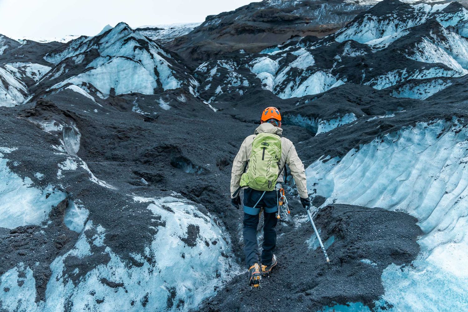A man in safety gear walks on a glacier