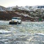 A modified jeep crosses an ice-covered river in Þórsmörk Iceland.