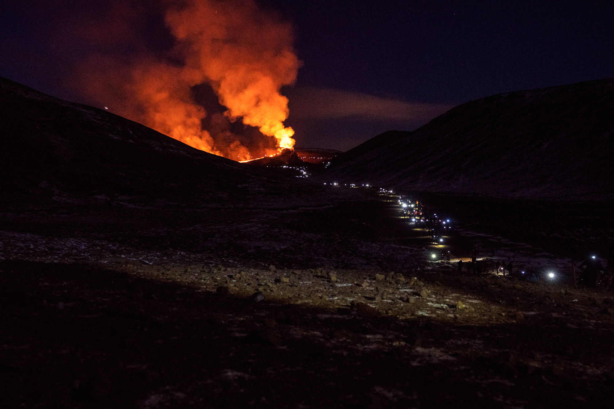 Many people on their way to and from a volcanic eruption in Iceland at night