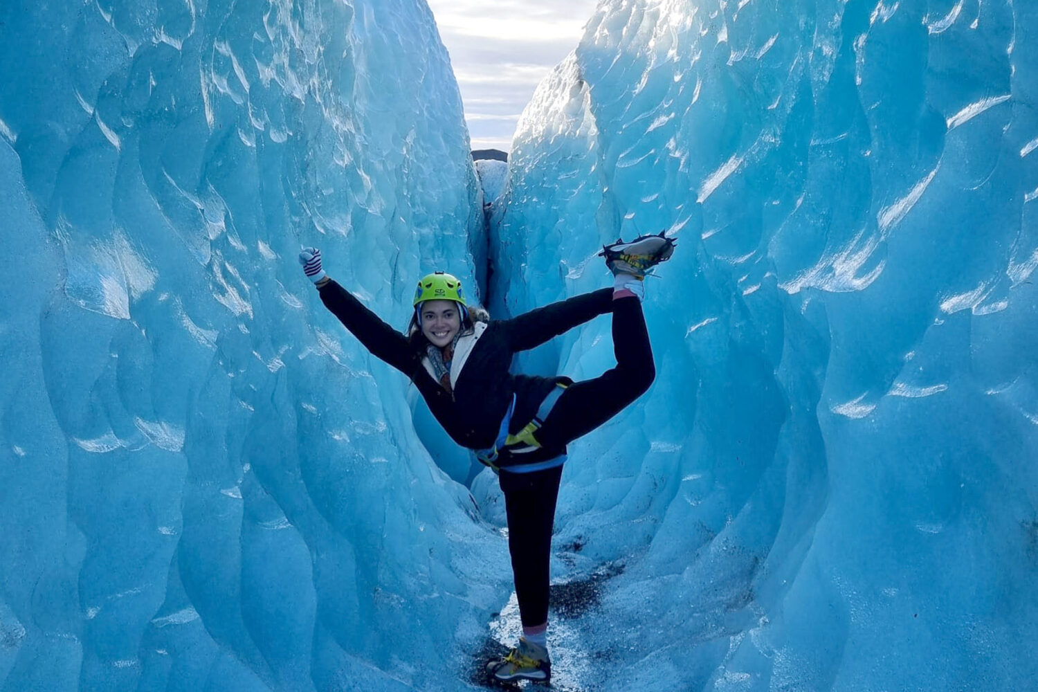 A girl does gymnastic exercises in an ice crevasse
