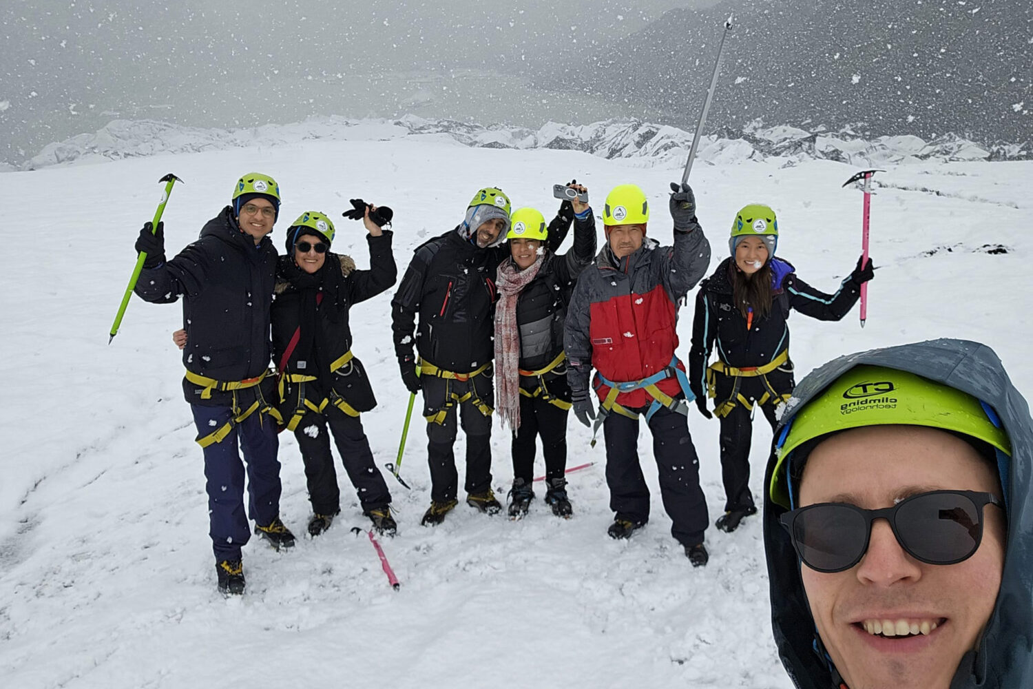 People taking a selfie on the glacier as it is snowing.