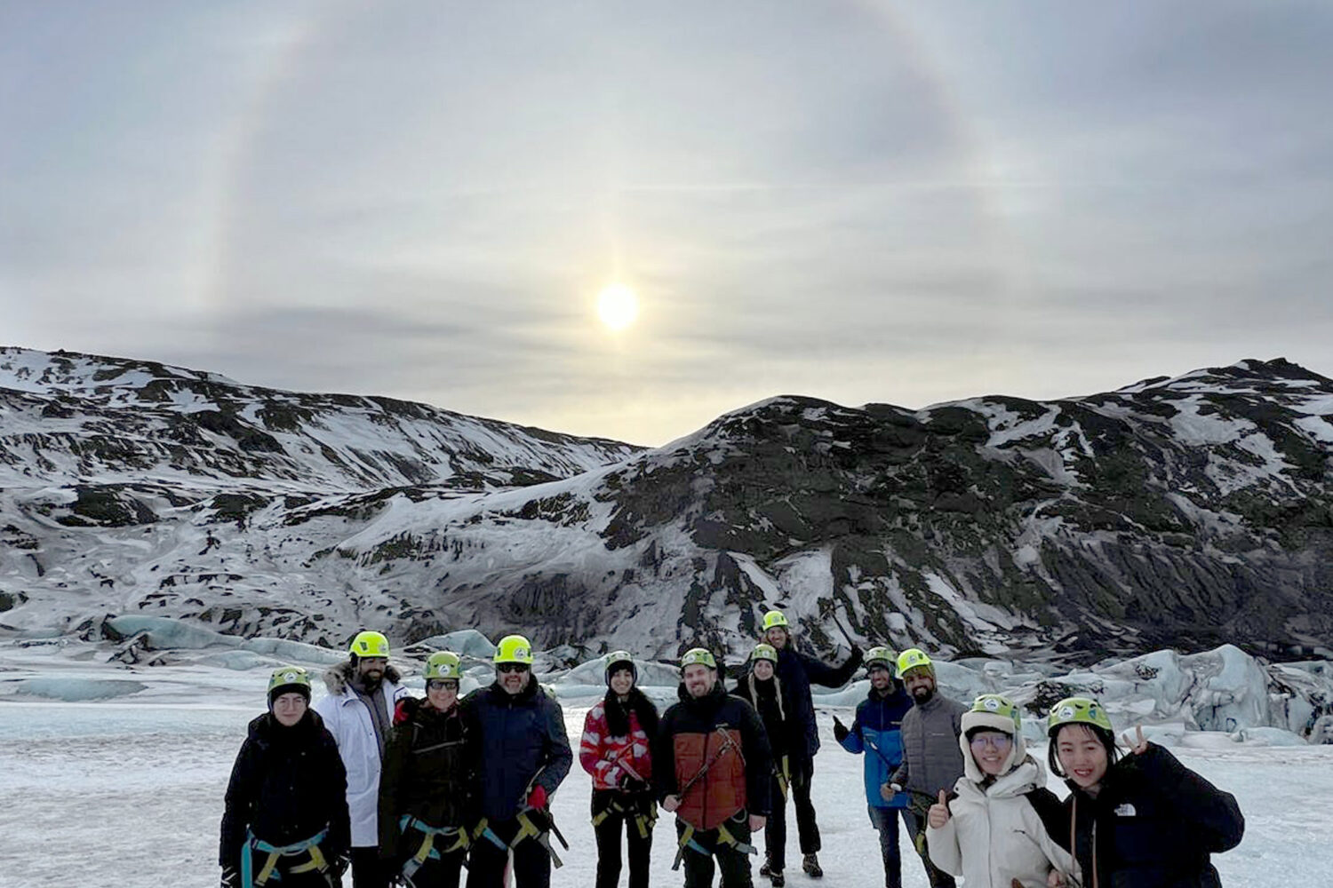 People standing on a glacier with a solar halo behind