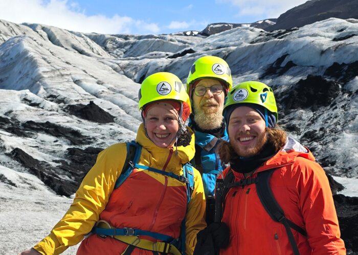 Family of three standing on the glacier.