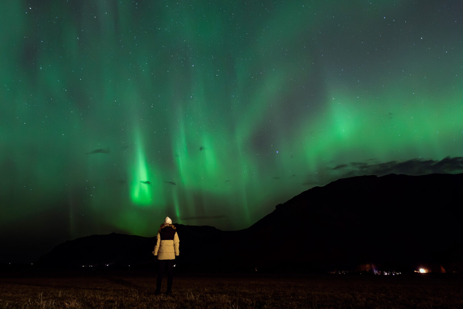 Woman looking at the Northern Lights in the Icelandic winter sky.