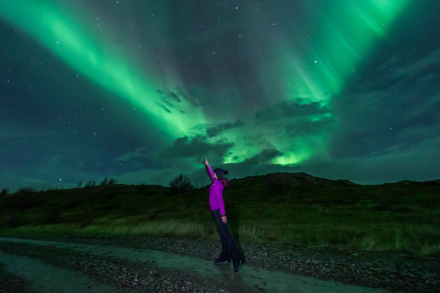 A womand standing under the Northern Lights in Iceland