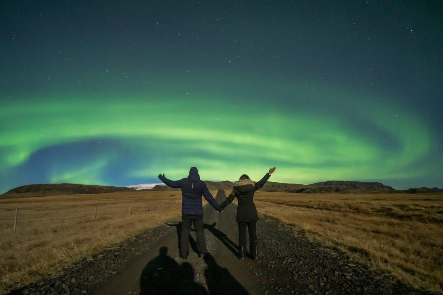 A couple standing underneath the auroras in Iceland.