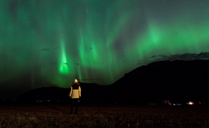 Woman looking at the Northern Lights in the Icelandic winter sky.