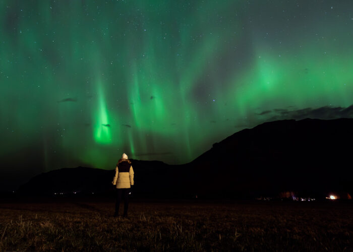 Woman looking at the Northern Lights in the Icelandic winter sky.